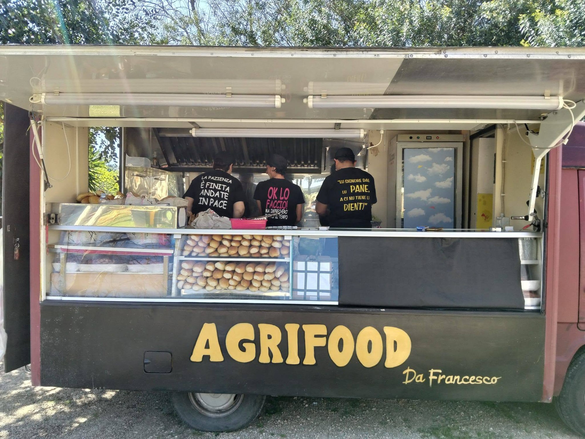 Food truck con insegna Agrifood Da Francesco, vetrina di panini e tre addetti in magliette nere dalle scritte ironiche