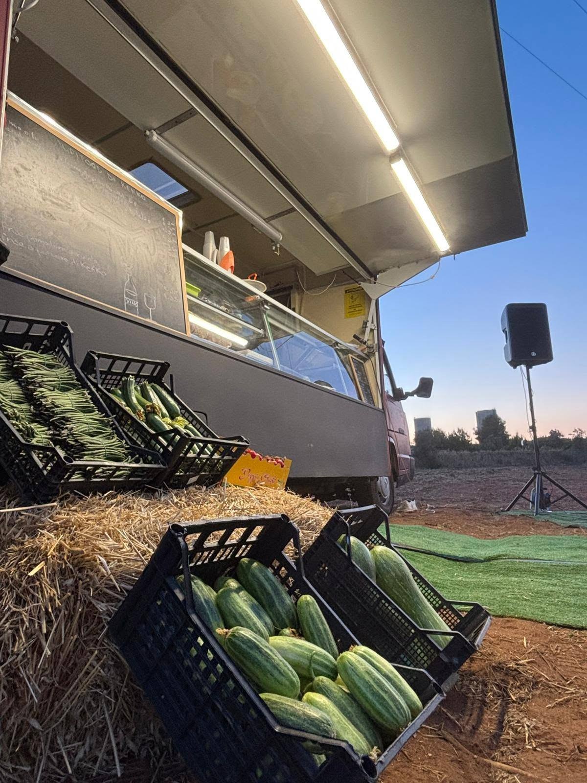 Cassette di zucchine e fagiolini su balle di paglia davanti al furgone illuminato di Agrifood da Francesco